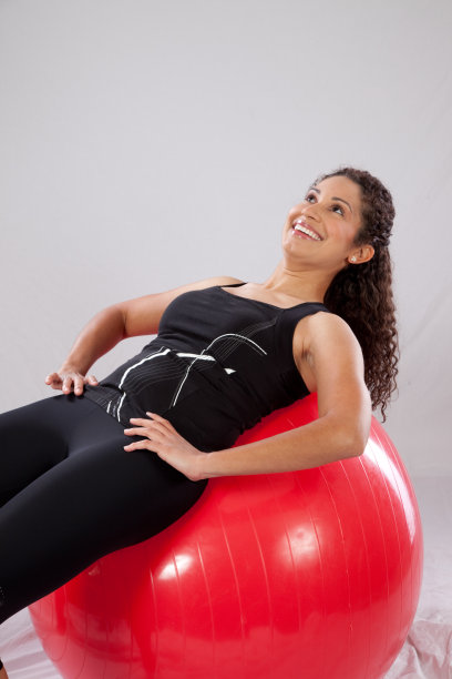 女人在红色健身球上做仰卧起坐图片下载