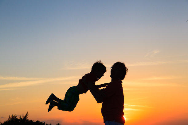 父亲和小儿子在夕阳下玩耍的剪影图片下载