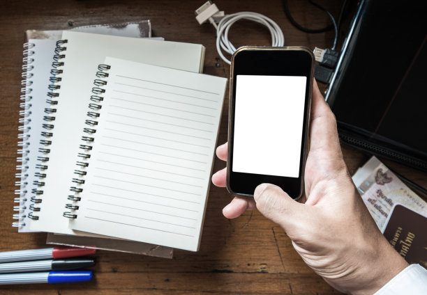 手持智能手机在凌乱的工作桌上，复古色调图片下载