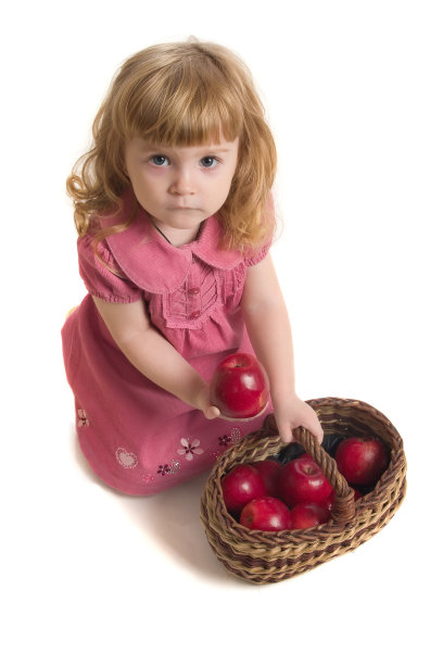 小女孩拿着一个装着红苹果的篮子。图片下载