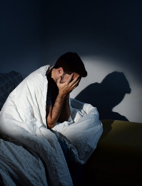 一个年轻人裹着羽绒被坐在沙发上，饱受抑郁之苦图片下载