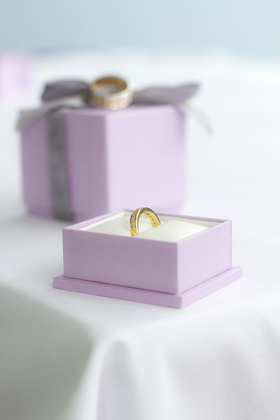 白色桌布上，粉色盒子里的金婚戒图片下载