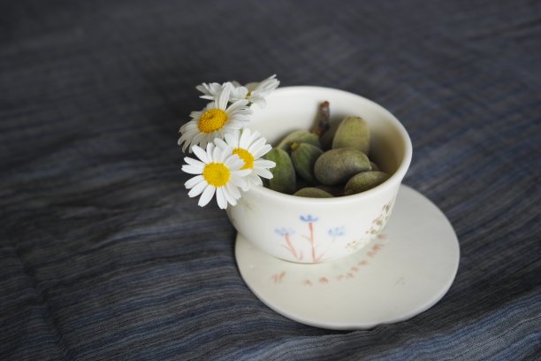 卡布奇诺咖啡杯中的雏菊和绿色杏仁图片下载