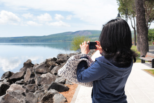 一名女性用智能手机为湖拍照图片下载