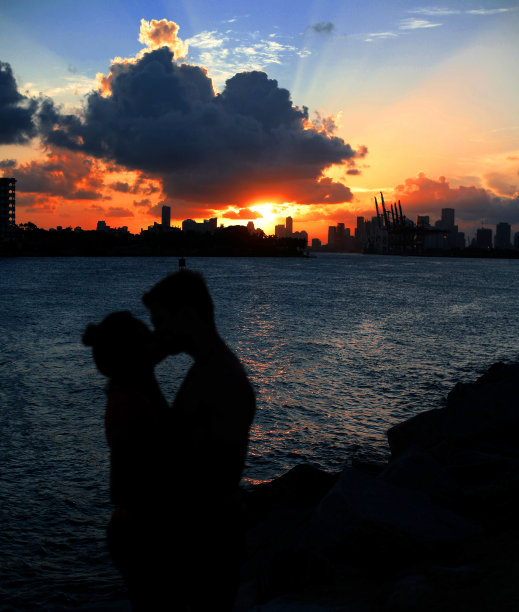 剪影情侣在日落时亲吻海边图片下载