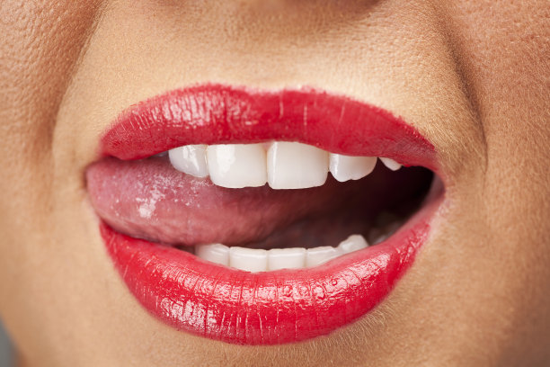 女人用鲜红的口红舔着她的牙齿图片下载