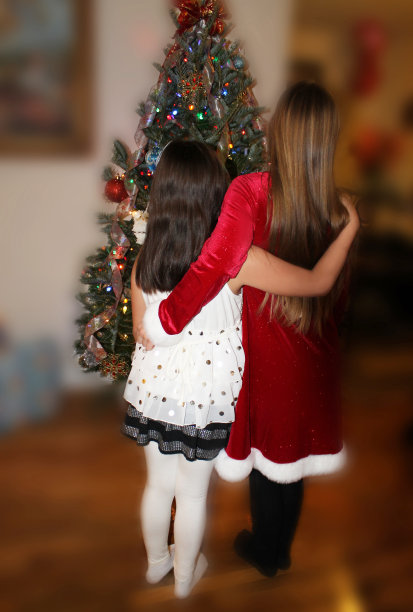 两个小女孩在圣诞树旁。图片下载