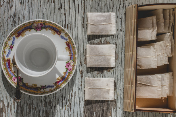 茶包摆放在木质背景上，配有茶杯和茶托图片下载