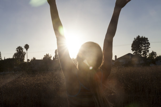 在太阳下的女人，手臂在头顶图片下载