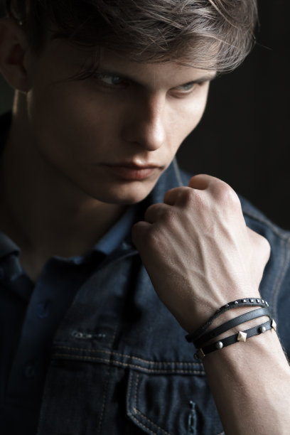 穿着牛仔夹克的时髦男士站着，手靠近头图片下载