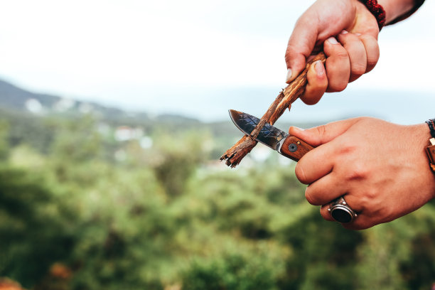 手持削刀雕刻木棒的男子图片下载