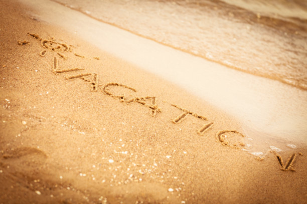 “假期”这个词写在沙滩上的沙子上图片下载