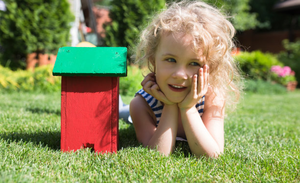 金发小女孩躺在草地上，手里拿着玩具图片下载
