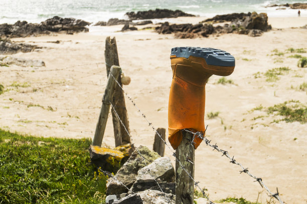 长筒靴越过沙滩上的栅栏图片下载