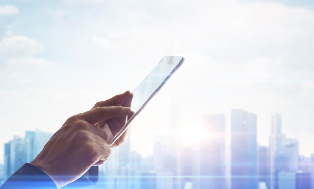 手与数字平板电脑在模糊的城市背景素材图片