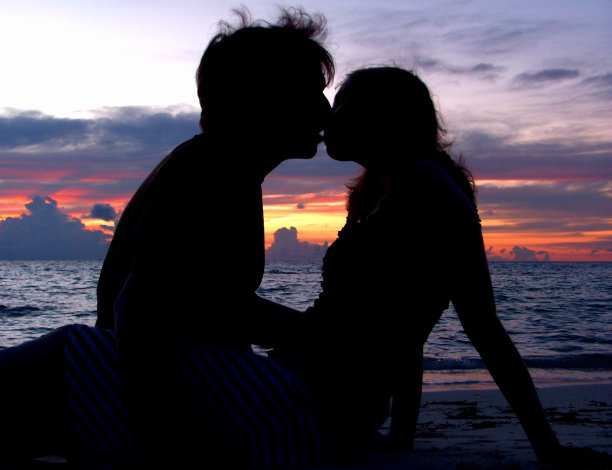 一对情侣在日落时分的海滩上接吻图片下载