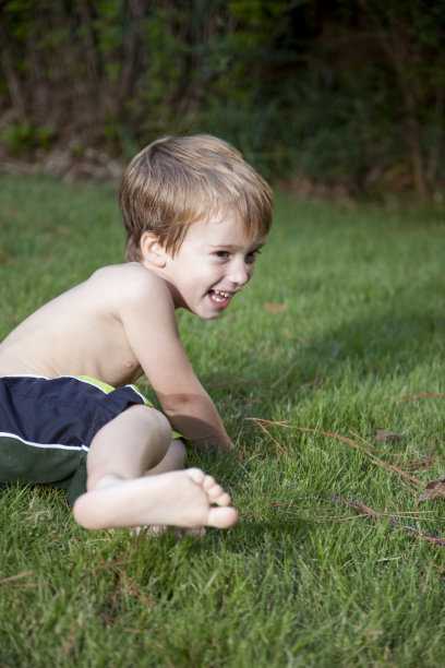 一个快乐的小男孩在草地上玩耍的照片图片下载