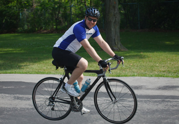 年轻的成年男性自行车骑手在公园的道路上骑自行车图片下载
