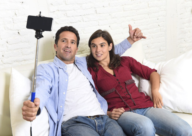 幸福的夫妇在沙发上自拍手机照片微笑图片下载