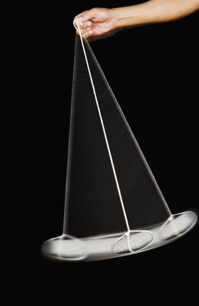 一个人的手摆动的石头钟摆的特写图片下载