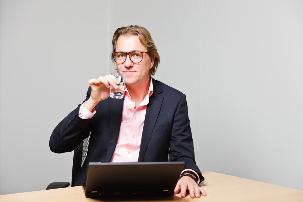 金发的年轻商人用手提电脑工作。图片下载