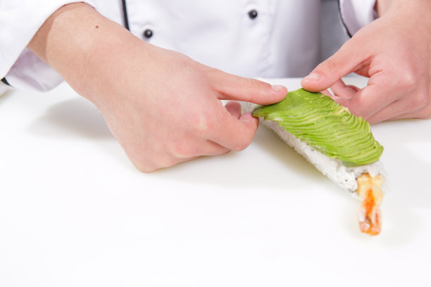 厨师把鳄梨放在寿司卷上图片下载