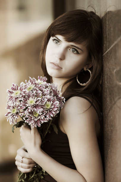 一个悲伤的年轻女子，在墙上放着花图片下载