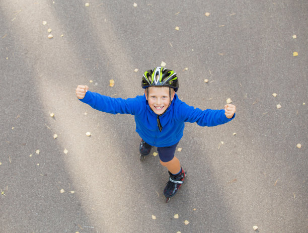 穿着旱冰鞋的快乐男孩举起双手图片下载