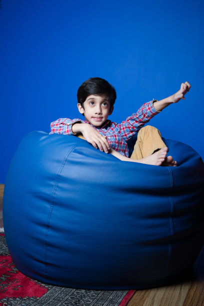 一个小孩坐在豆袋上。图片下载