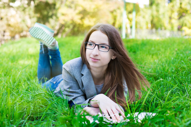 戴眼镜的学生在草地上思考图片下载