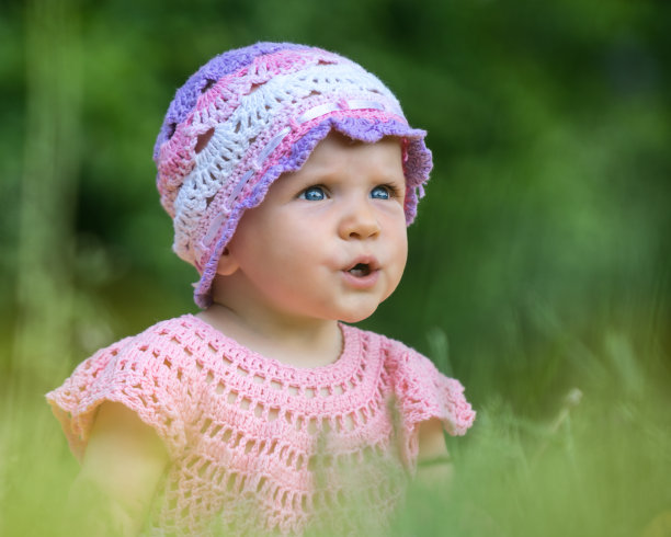 婴儿坐在户外阳光下的草地上图片下载