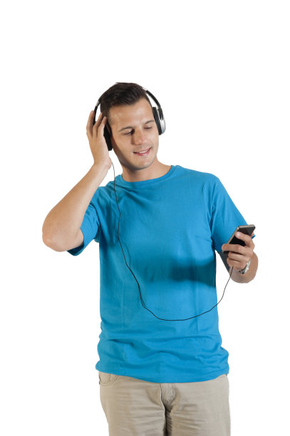 年轻英俊的享受音乐耳机从他的手机图片下载
