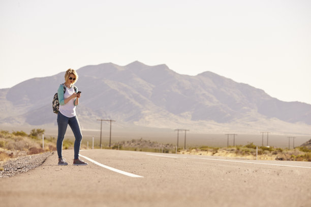 度假的女人在路上用手机搭车图片下载