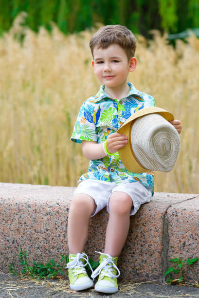 微笑的年轻时尚男孩拿着他的帽子，低头看图片下载