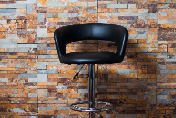 黑色皮革扶手椅背靠彩色砖墙内部图片下载