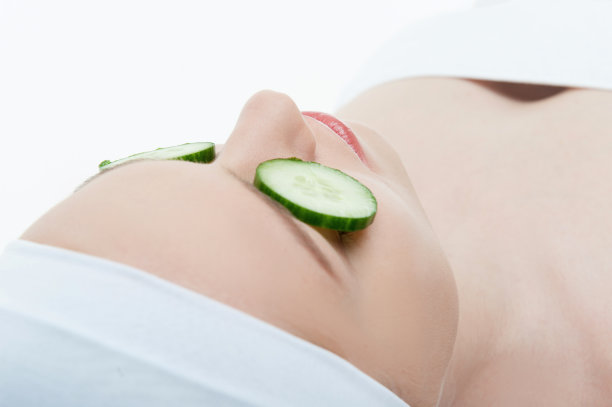 美丽的年轻女子接受黄瓜面膜在美丽图片下载