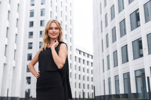 微笑的金发商务女性与红色的口红在城市的背景图片下载