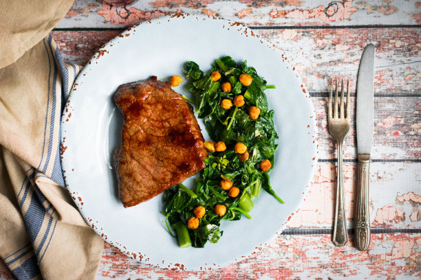 新鲜的牛排和绿色沙拉在质朴的木制背景图片下载