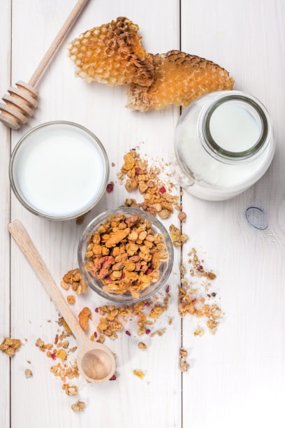 格兰诺拉麦片，牛奶和蜂蜜在玻璃杯里。图片下载