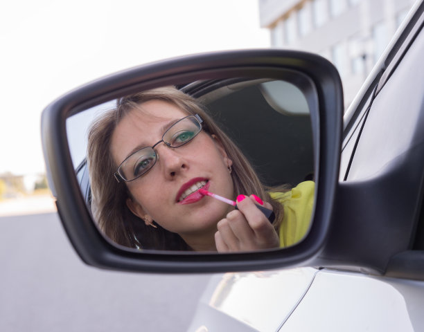 坐在车里的女人，看着镜子，涂着口红图片下载