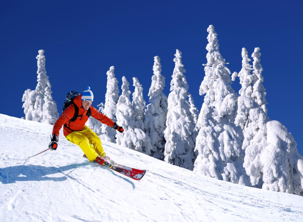 滑雪者在蓝天的映衬下，在高山中滑雪下山图片下载