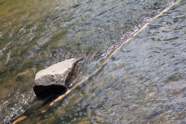 河中岩石与木棍呈对角图片下载