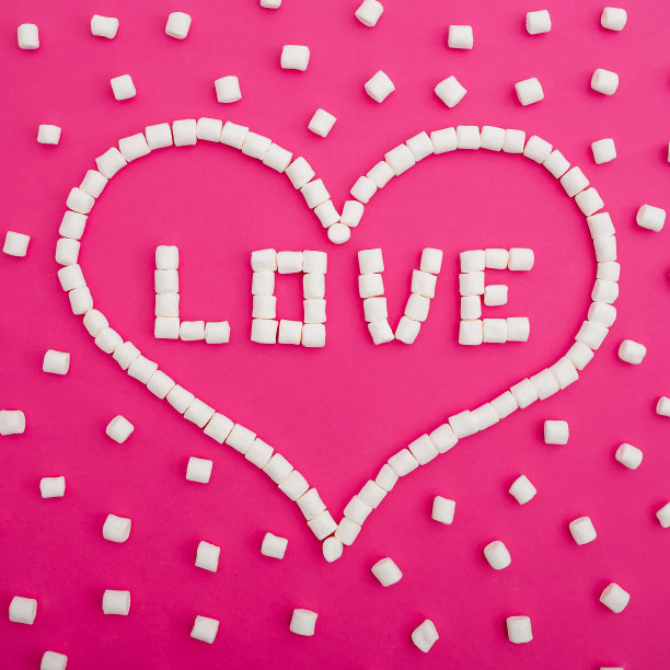 粉红色背景上分离的棉花糖。心中的“爱”字。平的。前视图。爱的背景图片下载
