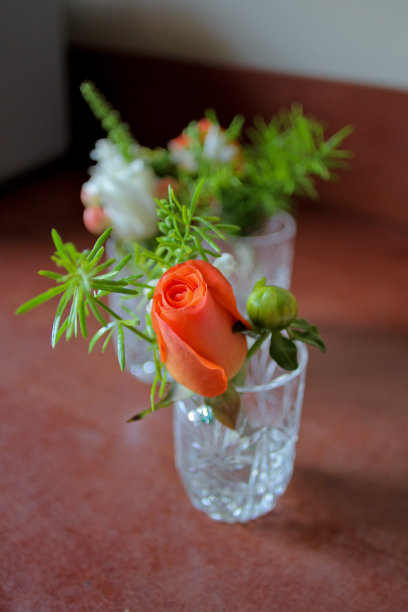 玻璃杯中镶有橙色玫瑰的婚礼胸花图片下载