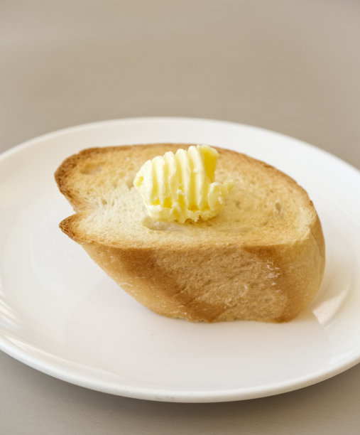 面包和黄油放在白盘子里图片下载