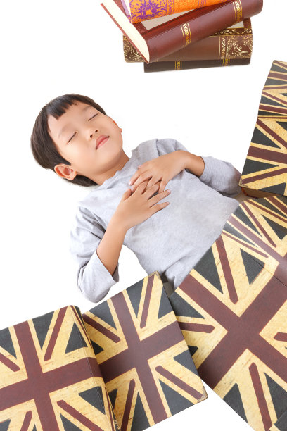 亚洲可爱的男孩在睡觉时被书覆盖。图片下载