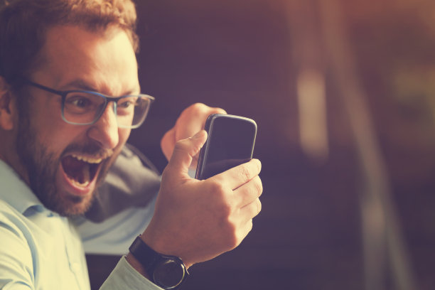 愤怒的家伙咬着电话。图片下载