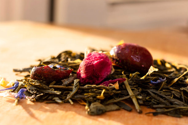 微距照片的茶与茶玫瑰。把一堆茶玫瑰和干木槿花放在一块木板上。红茶与天然玫瑰花特写。图片下载