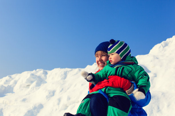 母亲和儿子在冬天的雪中玩耍图片下载