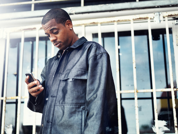 非裔美国人拿着智能手机站在废弃的商店前图片下载